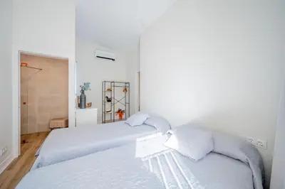 a white bedroom with two beds and a shower at The Nest Masia Can Tiranasi Relájate y Disfruta Escapada con Encanto Cerca de Barcelona- in Badalona