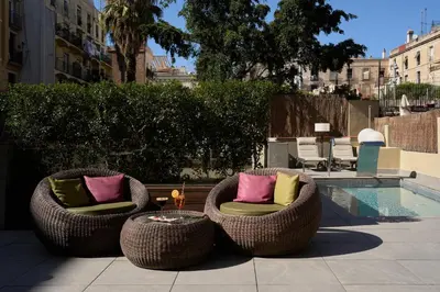 two wicker chairs with pillows sitting next to a pool at Catalonia Port in Barcelona