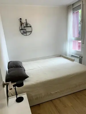 a white bedroom with a bed and a chair at Beach apartment 2 terraces with parking in Castelldefels