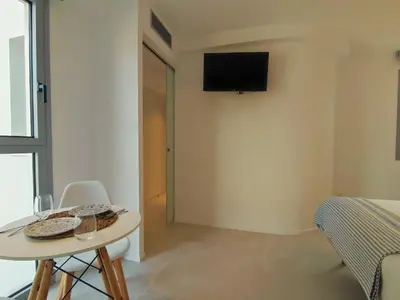 a room with a table and a tv on the wall at MYO Barcelona Hotel & Apartments in Castelldefels
