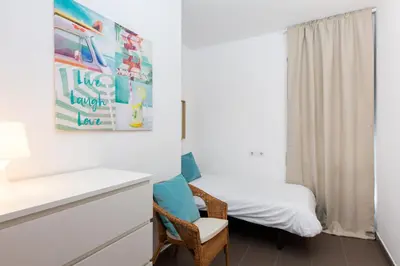 a small bedroom with a bed and a chair at Apartamentos Cornellalux in Cornellà de Llobregat