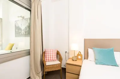 a bedroom with a bed and a chair and a mirror at Apartamentos Cornellalux in Cornellà de Llobregat