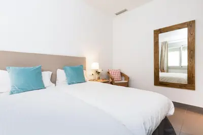 a bedroom with a large white bed and a mirror at Apartamentos Cornellalux in Cornellà de Llobregat