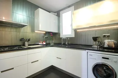 a kitchen with white cabinets and a washing machine at Three bedroom apartment in Gran de Gracia - You Stylish Apartments in Barcelona
