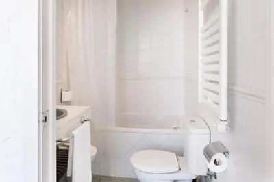 a white bathroom with a toilet and a sink at Rainbow Sitges in Sitges