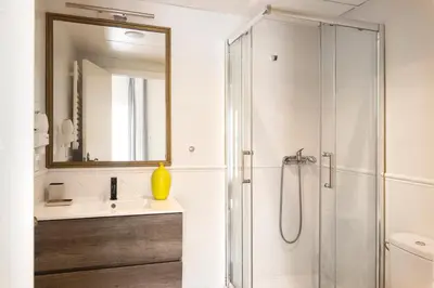 a white bathroom with a shower and a sink at Rainbow Sitges in Sitges