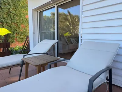 three chairs and a table on a porch with a window at Villa Leonardo in Castelldefels