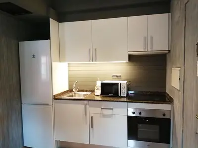 a kitchen with white cabinets and a sink and a microwave at Beachfront apartment Barceloneta Street in Barcelona