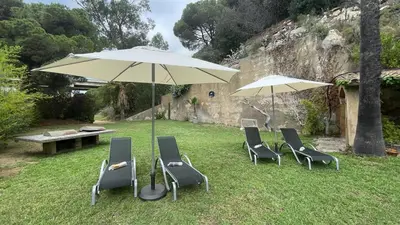 a group of chairs and an umbrella in the grass at Villa Exclusiva 12 Personas con Piscina, Barbacoa y Vistas al Mar en Maresme Barcelona in Sant Vicenç de Montalt
