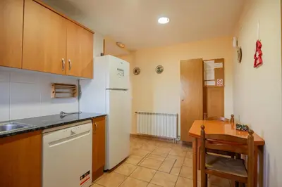 a kitchen with a white refrigerator and a table at Mas Prat in Pla del Panadés