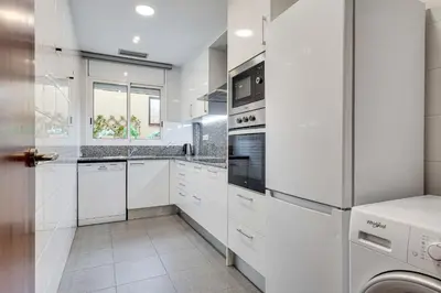 a white kitchen with white cabinets and appliances at Acogedor apartamento en el corazón de Sant Antoni in Barcelona