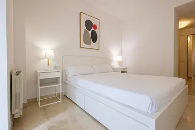 a white bedroom with a white bed and two lamps at Apartment for 6, spacious and bright in Bonanova in Barcelona