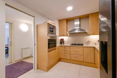 a kitchen with wooden cabinets and a stainless steel refrigerator at Apartment for 6, spacious and bright in Bonanova in Barcelona