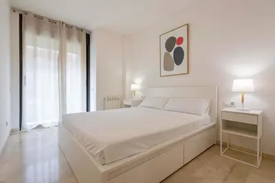 a white bedroom with a white bed and a window at Apartment for 6, spacious and bright in Bonanova in Barcelona