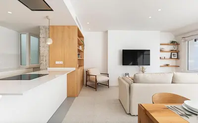 a white living room with a couch and a tv at Penthouse with Terrace near Gran Via and Camp Nou in Barcelona