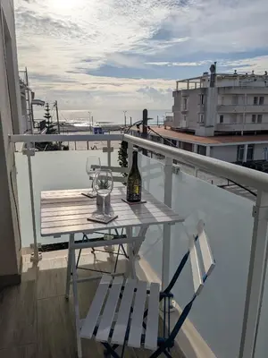 a table with a bottle of wine and two chairs on a balcony at La CASA BLAVA in Cubelles