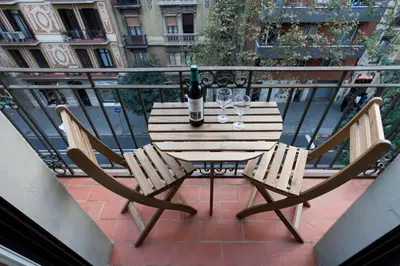 a table with two chairs and wine glasses on a balcony at 2582 - AB Sagrada Familia Marina in Barcelona