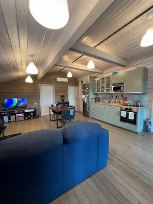 a living room with a blue couch and a kitchen at La Dacha Montanya in Seva