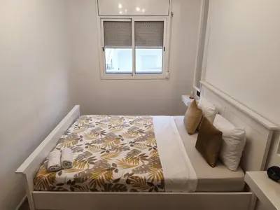 a bedroom with a bed with a comforter and a window at CasaKech in Vilanova i la Geltrú