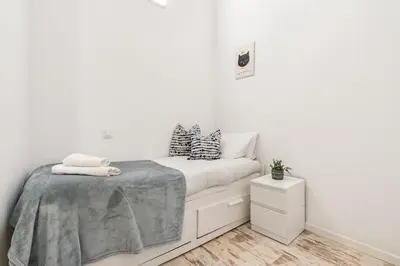 a white bedroom with a bed and a nightstand at Lodging Apartments Pere IV in Barcelona