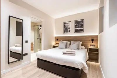 a white bedroom with a large bed and a mirror at Petit Luxe Mutua in Terrassa