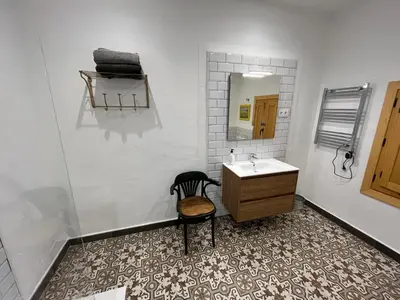 a bathroom with a sink and a chair and a mirror at La Casita Soler The Soler Cottage in Arbós