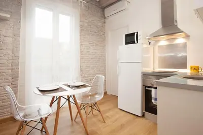a white kitchen with a white table and chairs at Flat with balcony next to the beach, SV in Barcelona