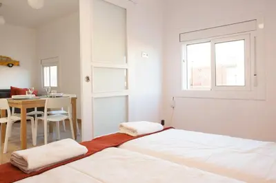a white bedroom with a bed and a table at Renovated apartment with sea view, VJ in Barcelona