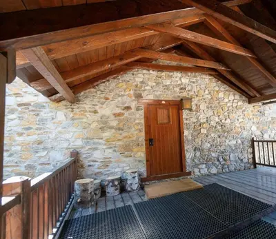 a stone building with a wooden door and a porch at Apartamento montaña en Arties in Artés