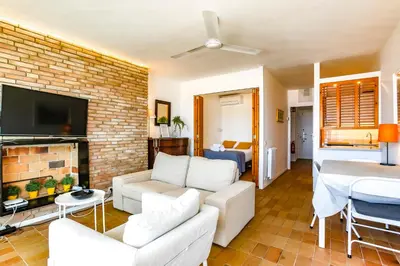 a living room with white furniture and a brick wall at Penelope Apart in Sitges