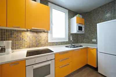 a kitchen with orange cabinets and a white refrigerator at Suites4days Sagrada Familia Apartment in Barcelona