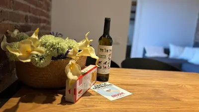 a bottle of wine and a vase of flowers on a table at Céntrico ático by Prestigi in Terrassa