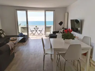 a living room with a table and chairs and the ocean at Port Alegre Mar in Sitges