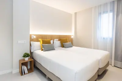 a large white bed in a room with a window at Fels Apartments in Castelldefels