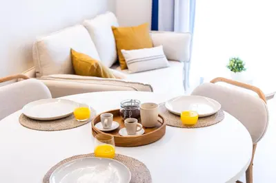 a living room with two tables with plates and orange juice at Fels Apartments in Castelldefels