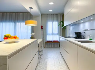 a kitchen with white cabinets and a bowl of fruit on the counter at Apartment Monet in Vilanova i la Geltrú