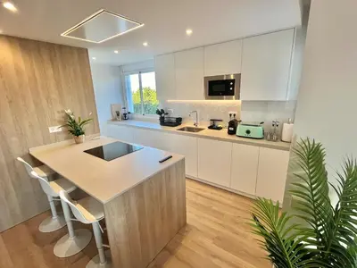 a kitchen with white cabinets and a kitchen island with chairs at Atico Barcelona Playa in Sant Adria de Besos