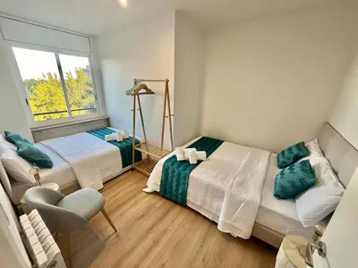 a bedroom with two beds and a chair and a window at Atico Barcelona Playa in Sant Adria de Besos
