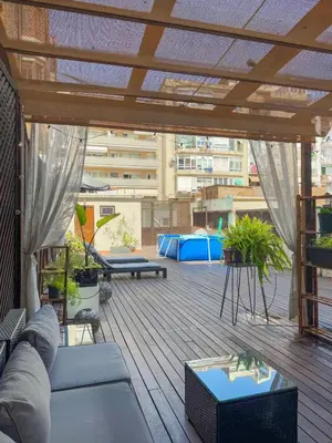 a patio with a couch and tables on a deck at Unique central home with large terrace & pool in Barcelona