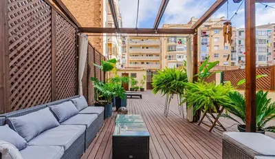 a rooftop patio with a couch and plants on a building at Unique central home with large terrace & pool in Barcelona