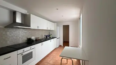 a kitchen with white cabinets and black counter tops at Piso Centro Badalona in Badalona