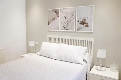 a white bedroom with a bed and three pictures on the wall at Cozy Apartment Rocamar in Sant Pere de Ribes