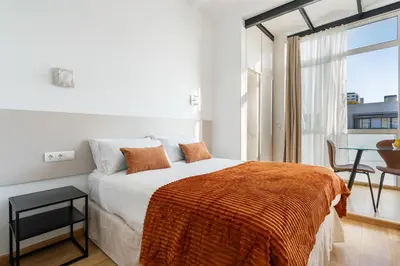 a white bedroom with a bed and a table at Sants Station Base 500Mb Wi-Fi AC in Barcelona