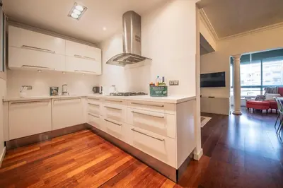 a kitchen with white cabinets and a hard wood floor at Apartamento de 3 habitaciones en Sant Antoni in Barcelona