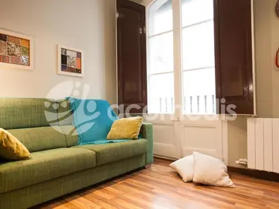 a living room with a green couch and a window at El Born Apartment - Santa Caterina Market - Walk to Cathedral & Picasso Museum in Barcelona