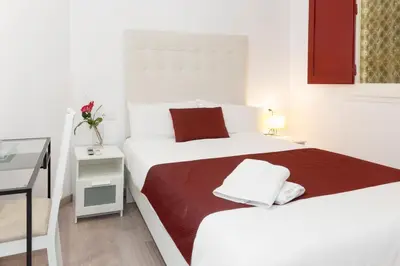 a white bedroom with two beds and a desk at BruStar Sagrada Familia in Barcelona