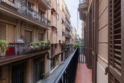 an alley between two buildings with plants on balconies at ApartEasy - PURE GRACIA, excellent location in Barcelona