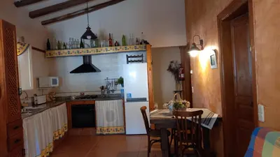 a kitchen with a table and a white refrigerator at Can Bicicleta de Dalt in Olesa de Bonesvalls