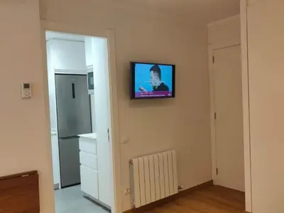 a living room with a television on the wall at Gran Vía de Carlos III B in Barcelona