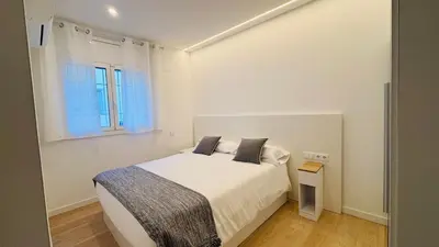 a white bedroom with a bed and a window at Apartamento familiar by prestigi in Terrassa